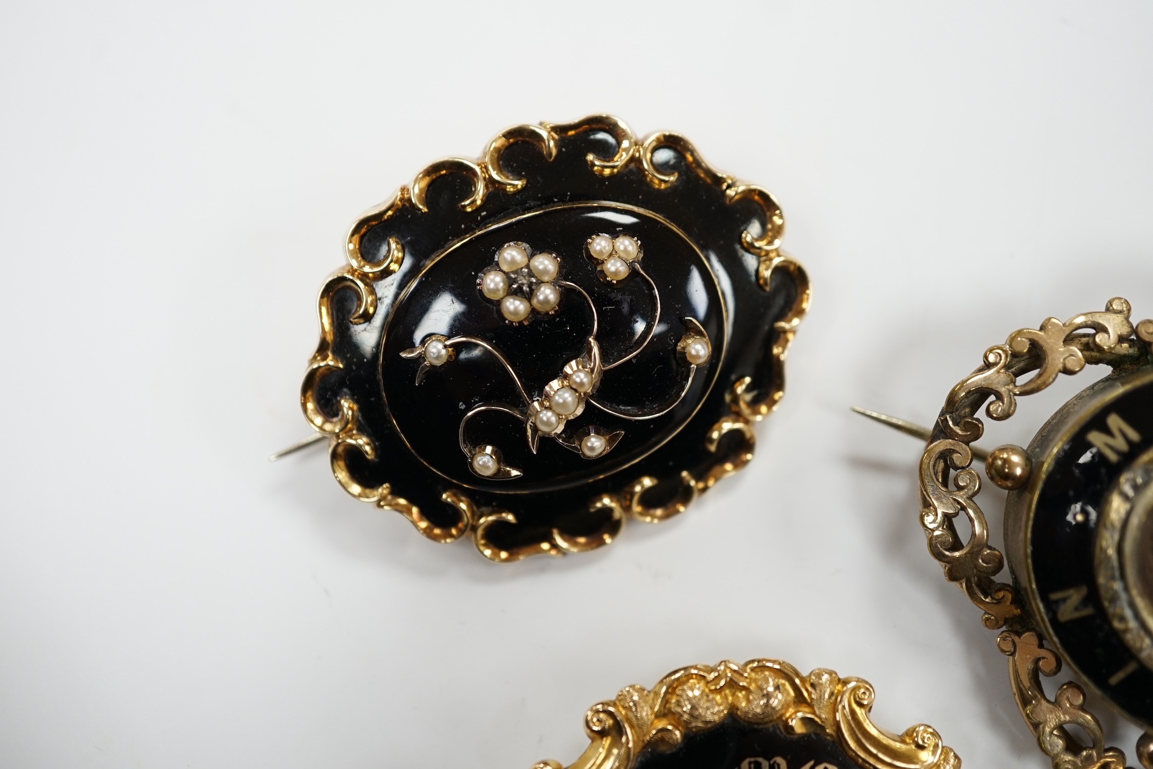 Three assorted Victorian mourning brooches, including two yellow metal, one set with seed pearls and diamond chip and inscribed and dated 1847, 48mm and two cameo shell set brooches.